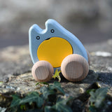 A blue and yellow coloured Bajo wooden push along ghost toy placed on a stone wall outdoors.
These heirloom quality wooden toys are part of a wide range available here at Babipur.