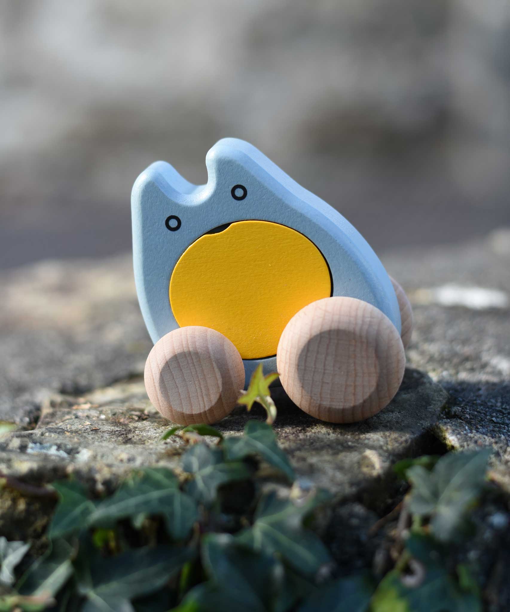 A blue and yellow coloured Bajo wooden push along ghost toy placed on a stone wall outdoors.
These heirloom quality wooden toys are part of a wide range available here at Babipur.