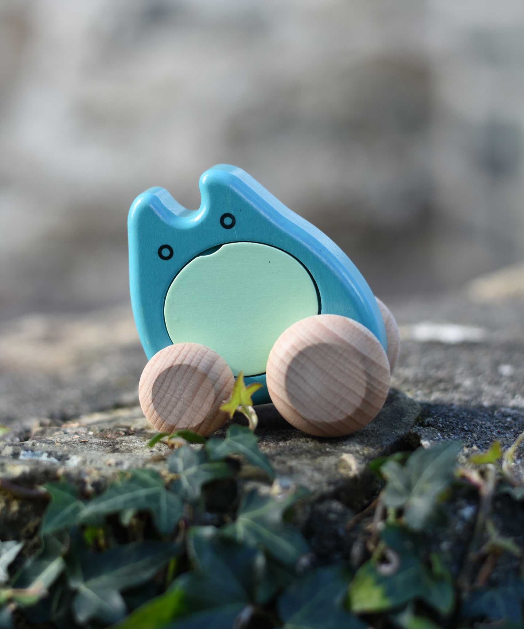 A turquoise coloured Bajo wooden push along ghost toy placed on a stone wall outdoors.
These heirloom quality wooden toys are part of a wide range available here at Babipur.