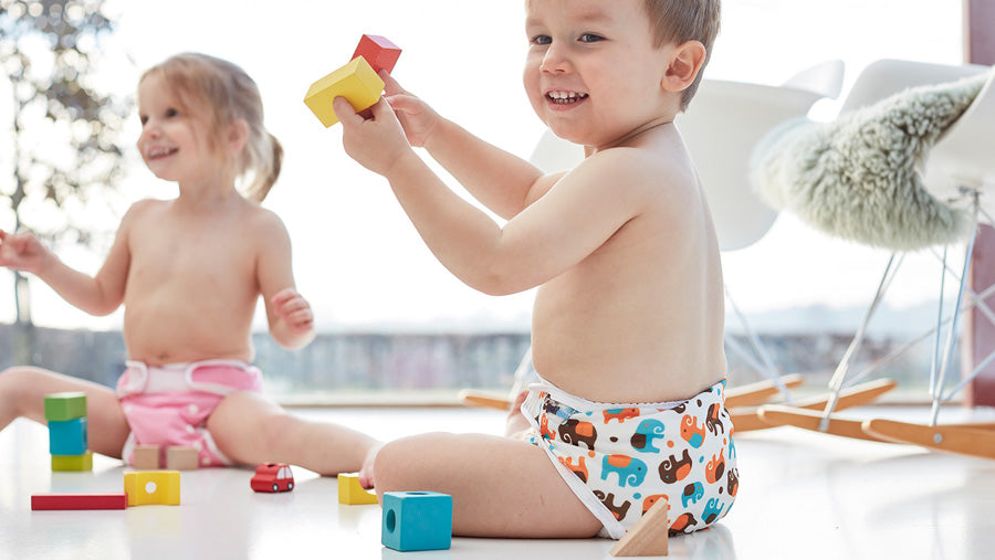 Two toddlers wearing Baminex cloth nappies with colourful nappy wraps