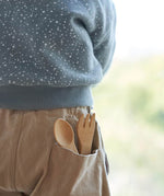 The Bambu Bamboo kids fork and spoon shown pepping out of a child's back pocket.