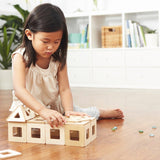 Girl playing with a set of Big Future Wooden Earth Tiles on a wooden floor in a white living room