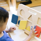 Child in a blue shirt opening the doors on a Big Future eco-friendly wooden latch board game