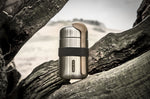 Black + Blum insulated stainless steel food flask with a wooden spoon and black elastic strap resting on a tree