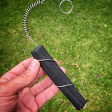 A close up of an adult hand holding the Black + Blum active charcoal water filter with metal coil showing the size