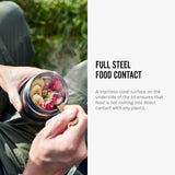 An image alongside text. An open Black + Blum insulated stainless steel food flask with food inside, the ladle is inside ready to scoop some of the food out. The text reads, full steel food contact. A stainless steel surface on the underside of the lid ensures that food is not coming into direct contact with any plastic.  Part of a wide range of reusable stainless steel lunch boxes here at Babipur.