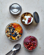 A top down view of the Black + Blum leakproof microwave safe glass lunchbowl showing different cereals inside the glass bowl and showing the silicone lid detail.