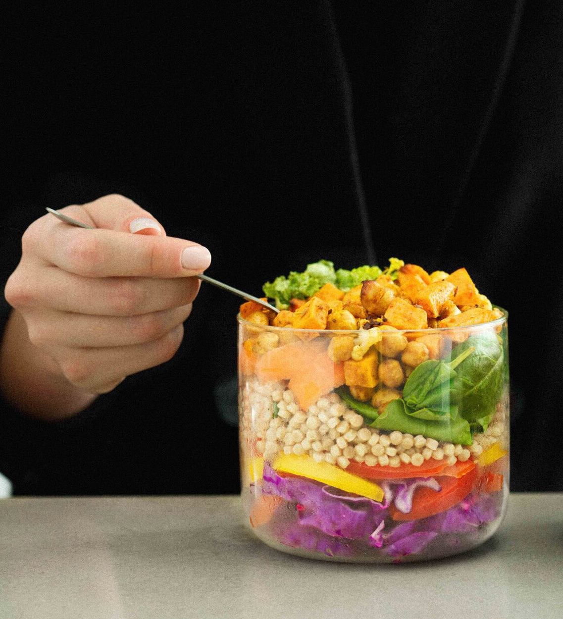 An adult eating a salad dish from the Black  + Blum glass bowl