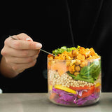 An adult eating a salad dish from the Black  + Blum glass bowl