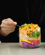 An adult eating a salad dish from the Black  + Blum glass bowl