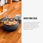 An open Black+Blum Leakproof Microwave Safe Glass Lunch Bowl filled with food. The text along side reads, wood fibre base. The protective and heat resistant base ensures the product can be handled straight from the microwave, with a silicone ring which stops the base from sipping or moving.