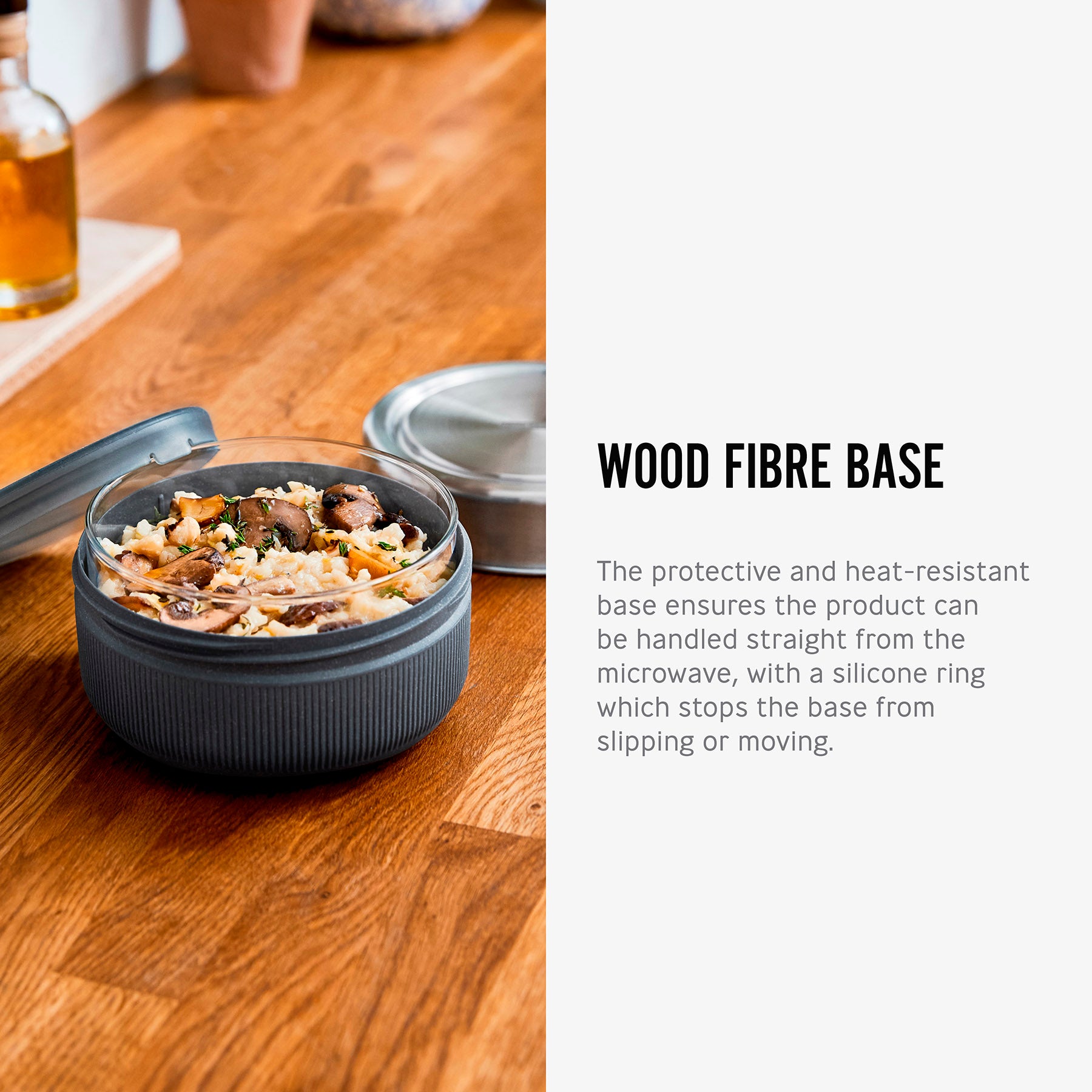 An open Black+Blum Leakproof Microwave Safe Glass Lunch Bowl filled with food. The text along side reads, wood fibre base. The protective and heat resistant base ensures the product can be handled straight from the microwave, with a silicone ring which stops the base from sipping or moving.