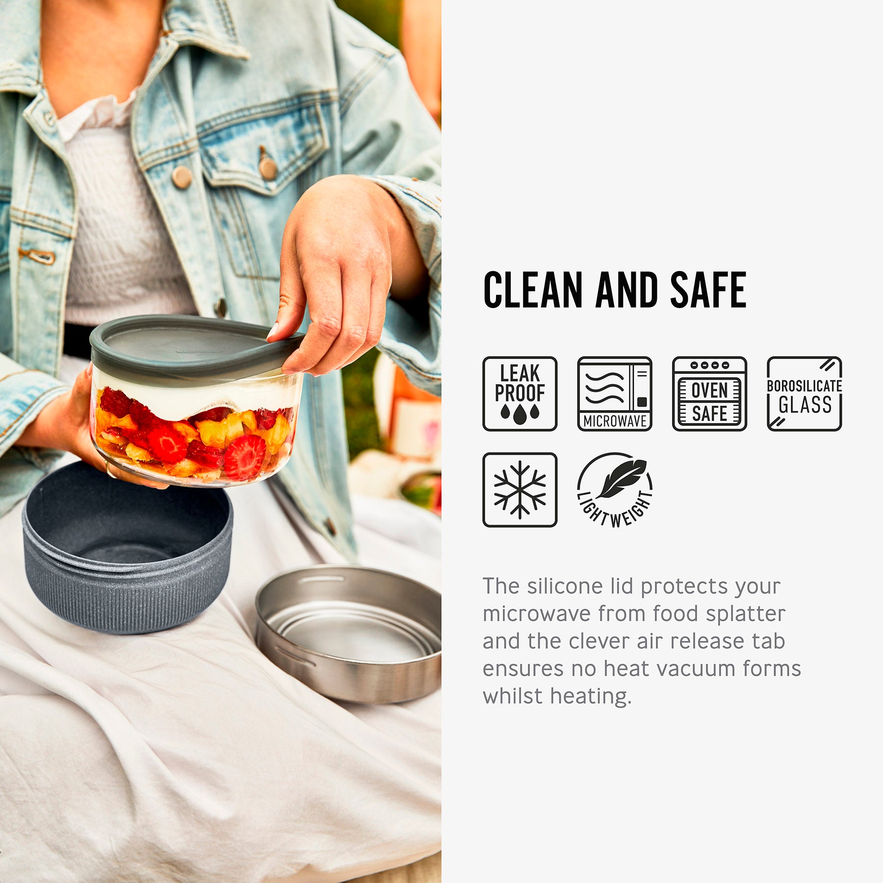 An image alongside text and symbols. The image shows someone lifting the silicone lift off a filled glass bowl from the Black+Blum Leakproof Microwave Safe Glass Lunch Bowl. The symbols are to show leak proof, microwave safe, oven safe, borosilicate glass, freezer safe and lightweight. The text reads clean and safe. The silicone lid protects your microwave from food splatter and the clever air release tab ensures no heat vaccum form whilst heating.