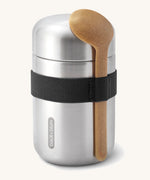 Black + Blum insulated stainless steel food flask with a wooden spoon available at Babipur. Features a black elastic strap to hold the spoon