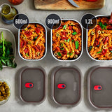 A top down view of the 3 diferent sized Black + Blum stainless steel lunch boxes next to eachother on a stone worktop with food inside and the grey lids next to each lunchbox