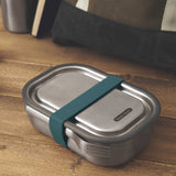 A large Black + Blum stainless steel lunchbox with a ocean blue silicone strap holding a stainless steel fork available at Babipur.