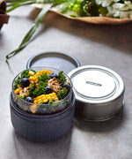 A close up of the Black + Blum leakproof microwave safe glass lunchbowl showing the protective leak proof stainless steel lid and wood case detail