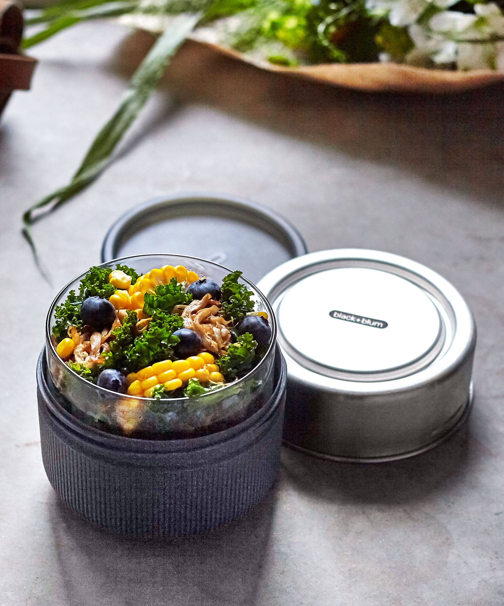A close up of the Black + Blum leakproof microwave safe glass lunchbowl showing the protective leak proof stainless steel lid and wood case detail