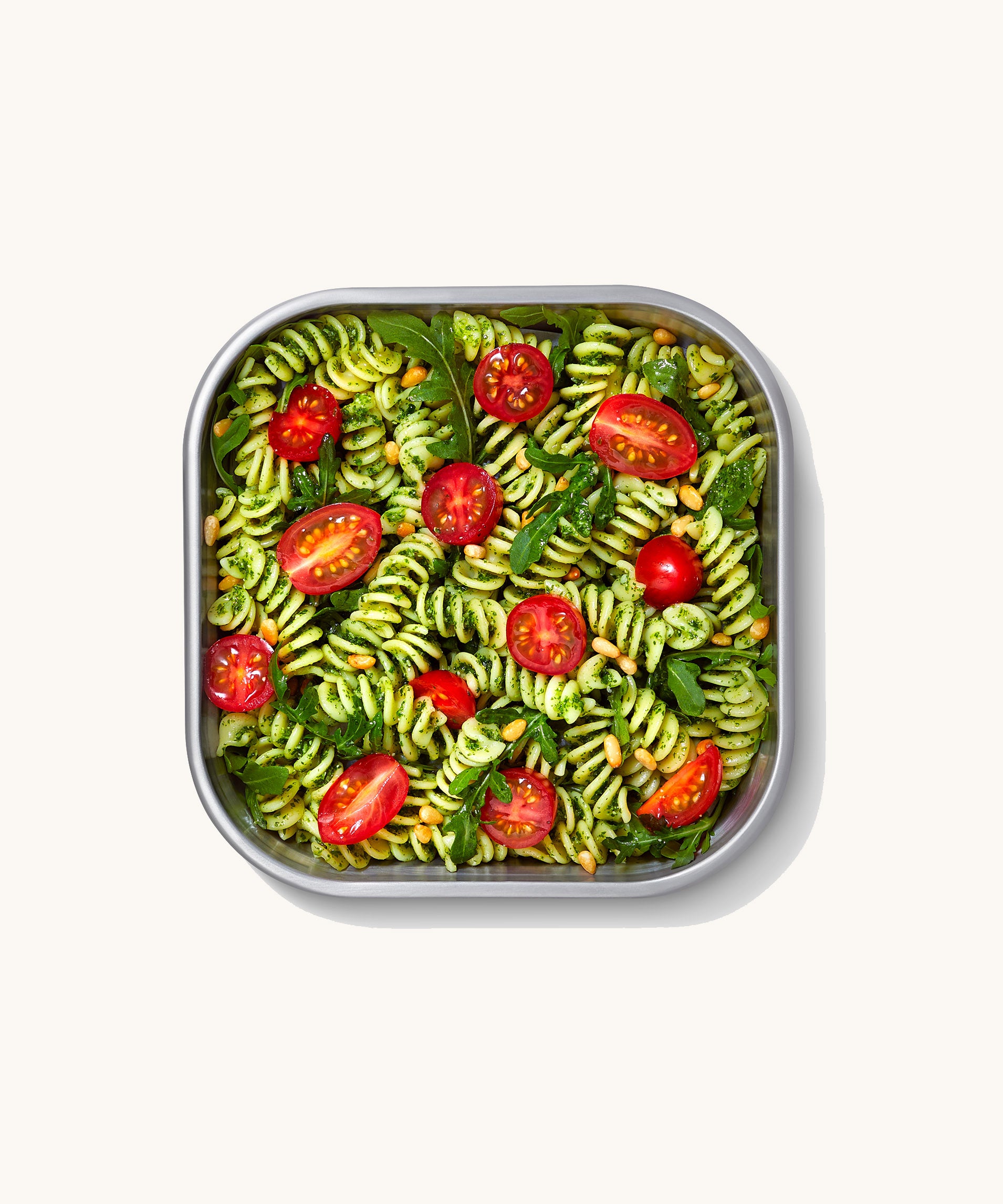 A close up of a Black + Blum square stainless steel leakproof microwave safe lunchbox showing a pasta dish inside the lunchbox