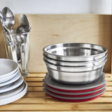 A close up of 3 Black + Blum stainless steel bowls on a wooden racking with the lids resting underneath