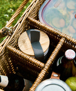 A close up of the Black + Blum stainless steel cups in a picnic basket showing the protective bamboo lid detail