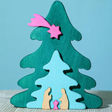 A Bumbu Christmas Tree Nativity Puzzle in a Fuchsia colour way placed on a wooden surface.