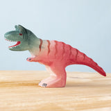 Bumbu Toys Big Carnotaurus dinosaur wooden figure placed on a wooden surface. The handmade dinosaur figure is part of a wide range of wooden animal figures here at Babipur.