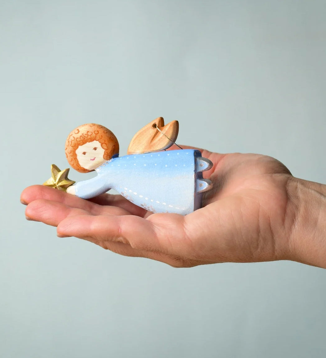 A Bumbu Christmas Angel placed in the palm of an adult's hand.