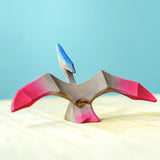 Bumbu Wooden Pteranodon Dinosaur. The toy sits on a wooden surface against a blue background.