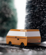 CandyLab VW T3 Campervan in brown - back view, driving down a snowy road in the forest.