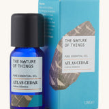 Atlas Cedar pure essential oil in a blue glass bottle in front of a decorative blue cardboard box.