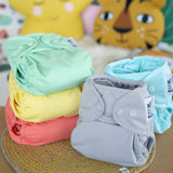 The Close Parent Pop-In reusable cloth nappies with popper fastenings, in pastel colours.