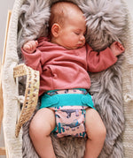 A baby wearing the Close Pop-In +bamboo reusable cloth nappy with adjustable velcro closures, in a ferret print