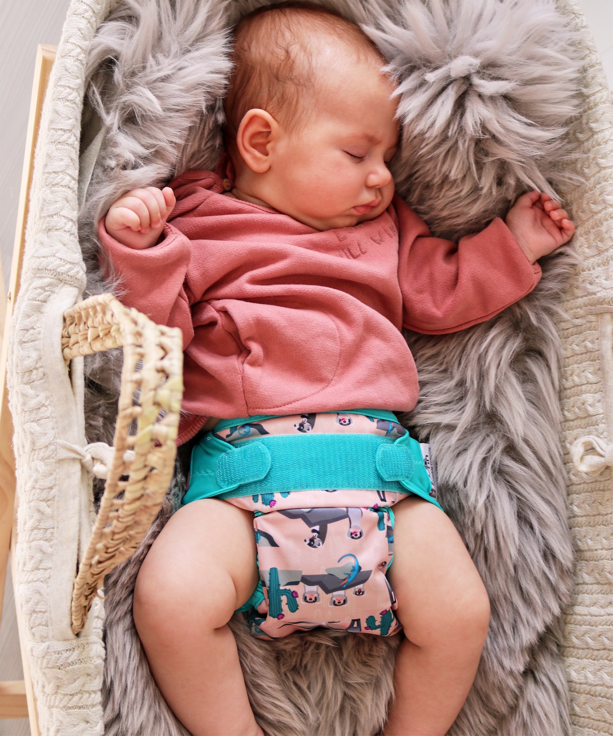 A baby wearing the Close Pop-In +bamboo reusable cloth nappy with adjustable velcro closures, in a ferret print