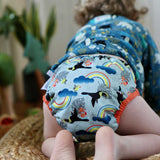 A baby wearing The Close Pop-In +bamboo reusable cloth nappy with adjustable popper closures, in a toucan print