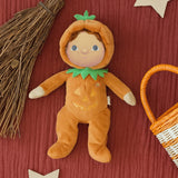 A flatlay image including the Olli Ella Jack-O-Lantern pumpkin dinky dinkum doll. next to a broomstick and basket. Doll is available at Babipur.