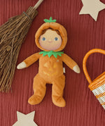 A flatlay image including the Olli Ella Jack-O-Lantern pumpkin dinky dinkum doll. next to a broomstick and basket. Doll is available at Babipur.
