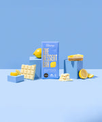 The Divine White Chocolate Lemon Cheesecake Dessert Bar shiwn in it's wrapping with an unwrapped bar by it's side.