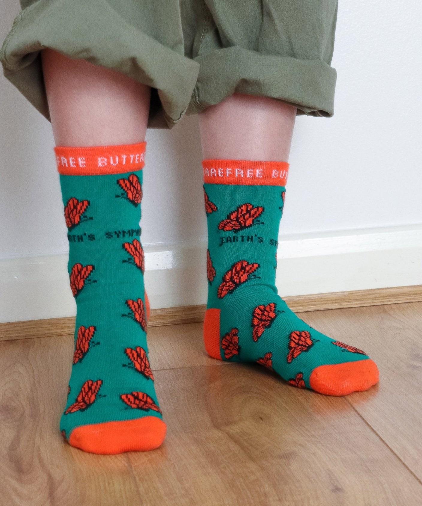 A close up of a child wearing the Eco Kiddies organic cotton butterfly socks showing the cute orange butterfly design and orange trim detail