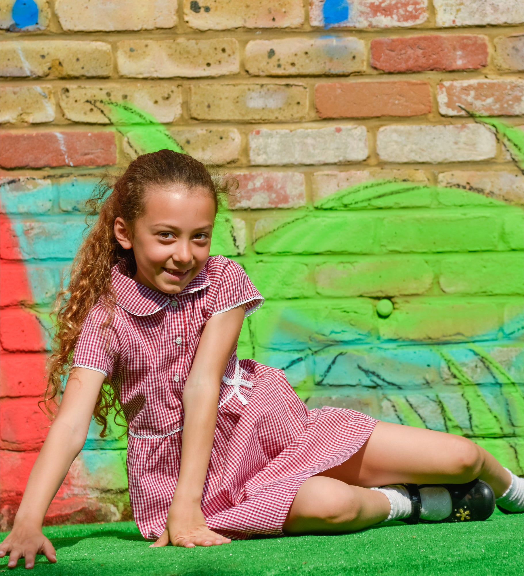 A little girl wearing The Eco Outfitters organic and fair trade cotton school summer dress in red gingham.