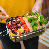 The Elephant Box Jumbo 2-in-1 stainless steel lunch box, the small box is filled with fruits and is slotted into the bigger box, which is filled with sandwiches and tomatoes.