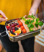 The Elephant Box Jumbo 2-in-1 stainless steel lunch box, the small box is filled with fruits and is slotted into the bigger box, which is filled with sandwiches and tomatoes.