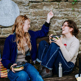 2 women sitting on a bench and eating from their Elephant box bowls. The medium and large bowls are available at Babipur. Features a removable lid and a silicone base.