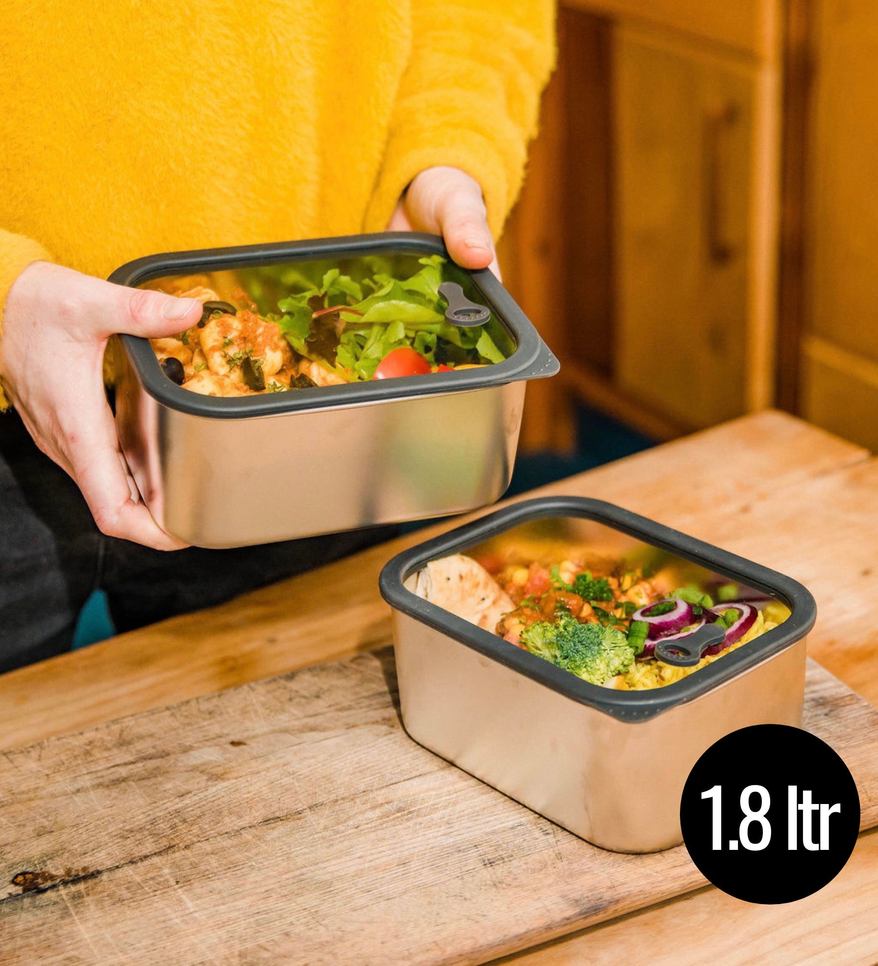 A man holding he Elephant Box Prep & Store medium food storage container with a grey silicone seal and see through glass lid.