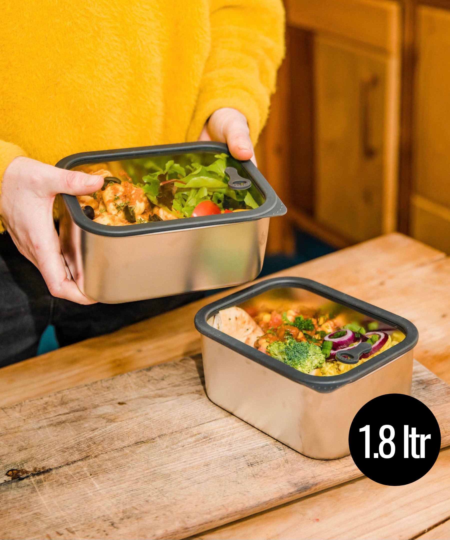 A man holding he Elephant Box Prep & Store medium food storage container with a grey silicone seal and see through glass lid.