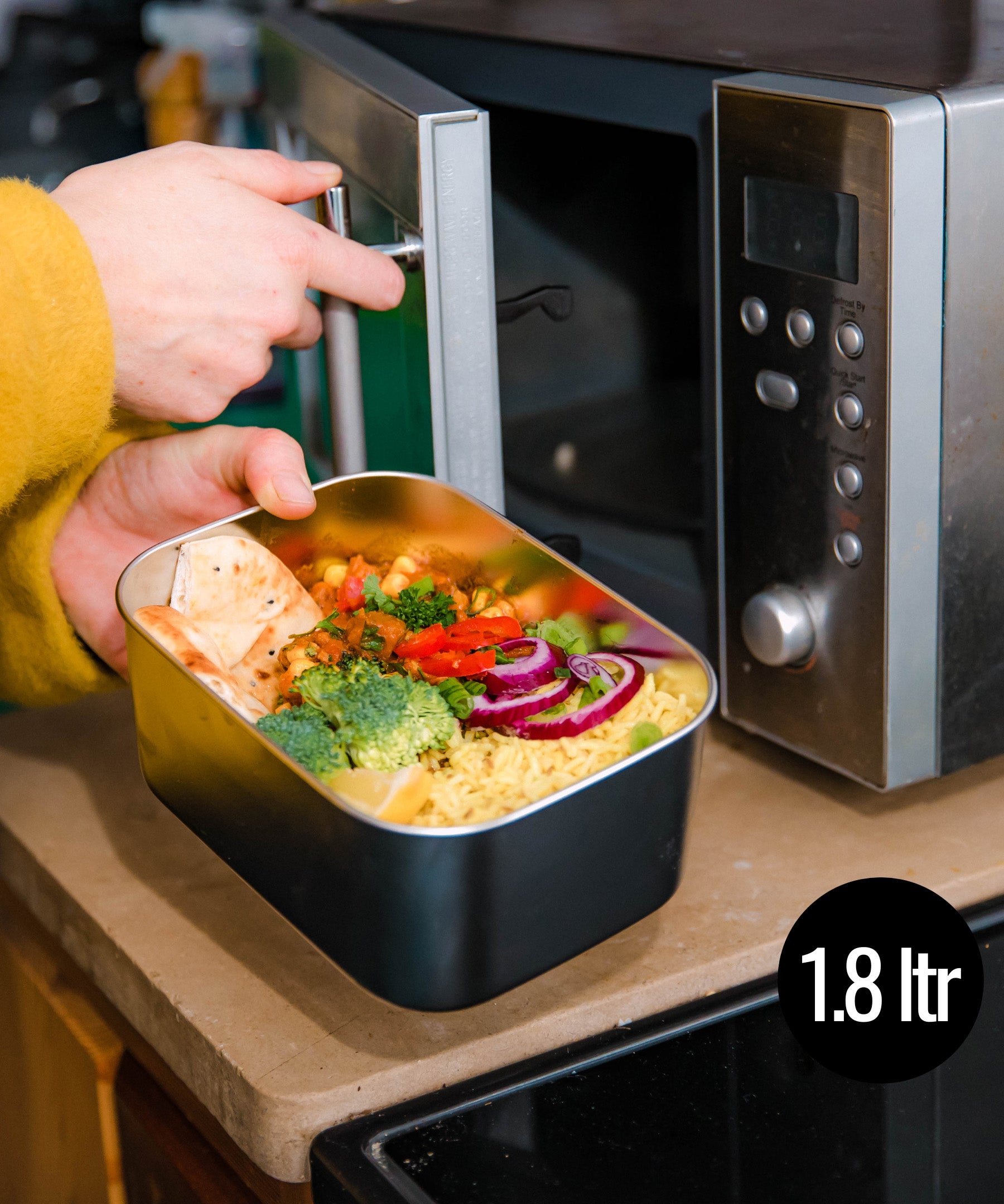 A man putting the Elephant Box Prep & Store medium food storage container in the microwave.