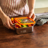 A man closing the Elephant Box Small Prep & Store food storage container, with an orange silicone lid.