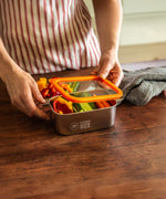A man closing the Elephant Box Small Prep & Store food storage container, with an orange silicone lid.