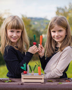Two children playing with the Erzi Vegetable Patch Wooden Play Food Set. The child on the left is holding the red radish