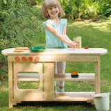 A child playing outdoors with the Erzi wooden toy kitchen and toy pots and pans.